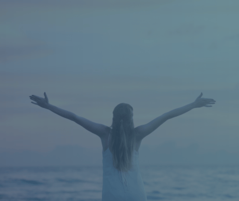 Girl on the beach holding out her arms.