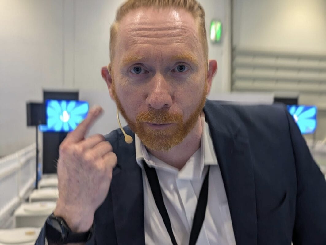 Gameshow host points are microphone he is wearing.