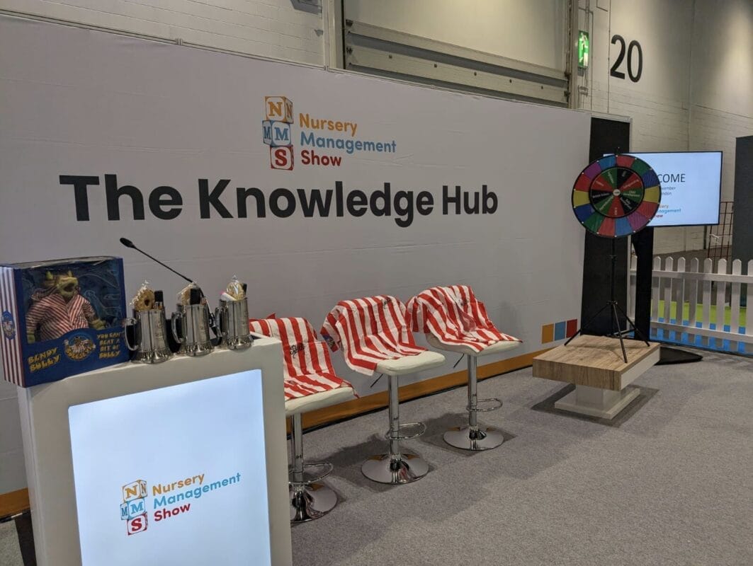 Set-up of the gameshow at the nursery management show, with prizes on the desk, a dart board at the back, and stripey shirts on the chairs.
